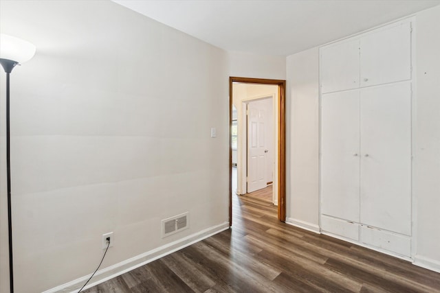 unfurnished bedroom with a closet and dark hardwood / wood-style floors