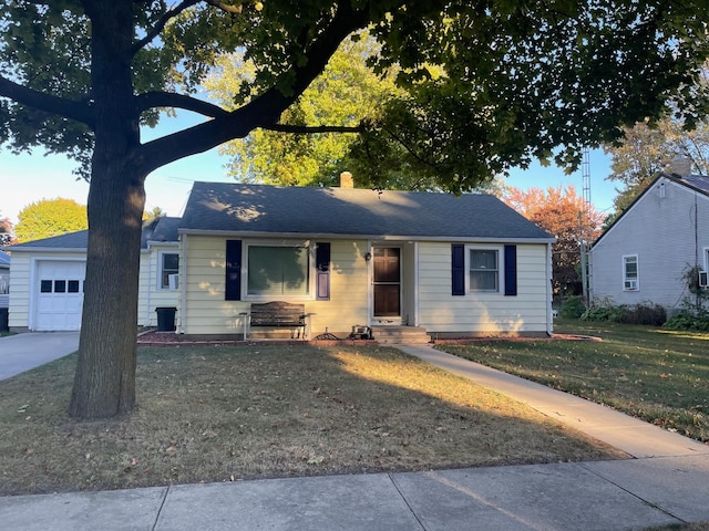 view of front of property with a shingled roof, a front lawn, entry steps, a chimney, and a garage