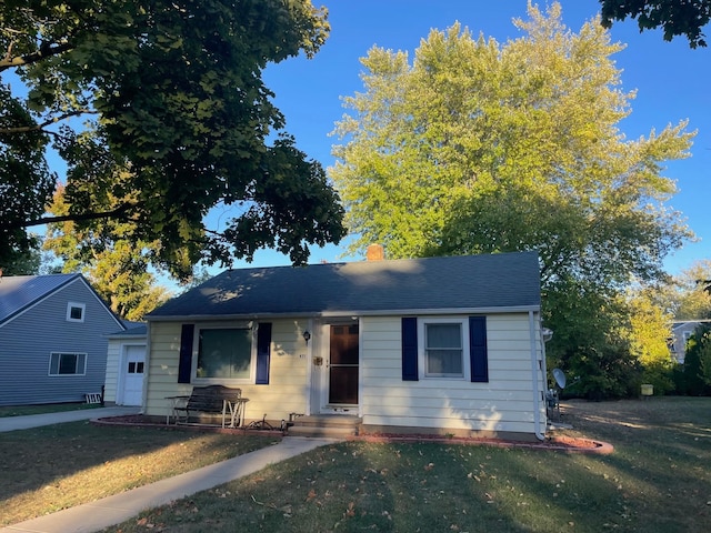 bungalow featuring roof with shingles, a chimney, and a front yard