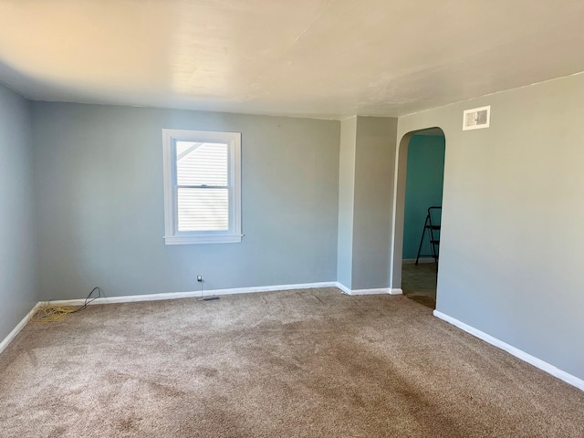 spare room featuring baseboards, arched walkways, carpet, and visible vents