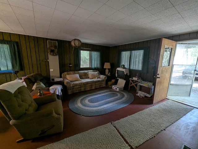 living room featuring plenty of natural light, concrete flooring, and wooden walls