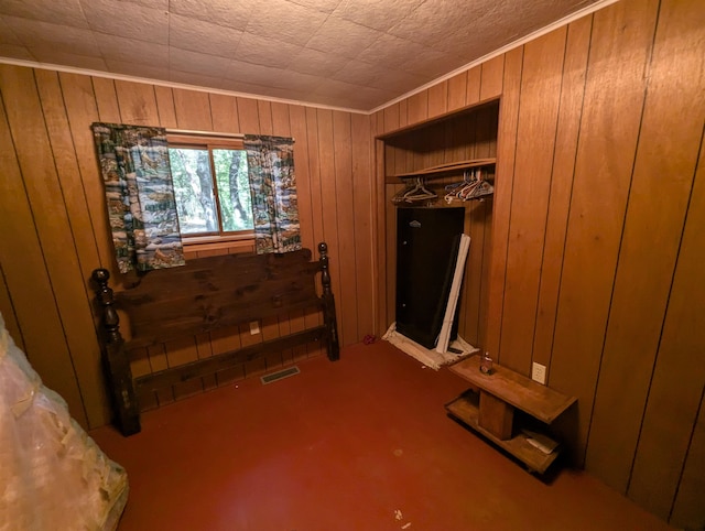 carpeted bedroom with a closet and wooden walls