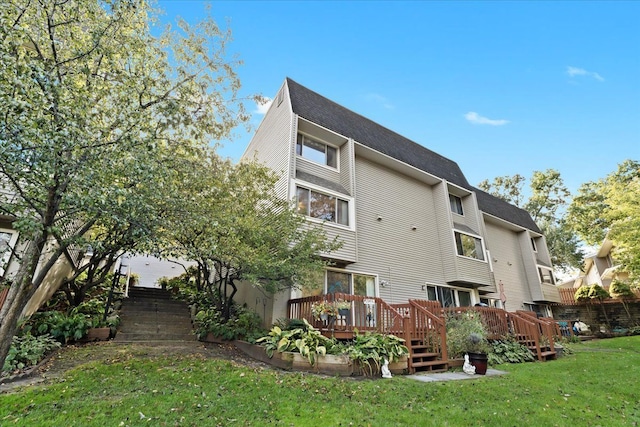 rear view of house featuring a deck and a lawn