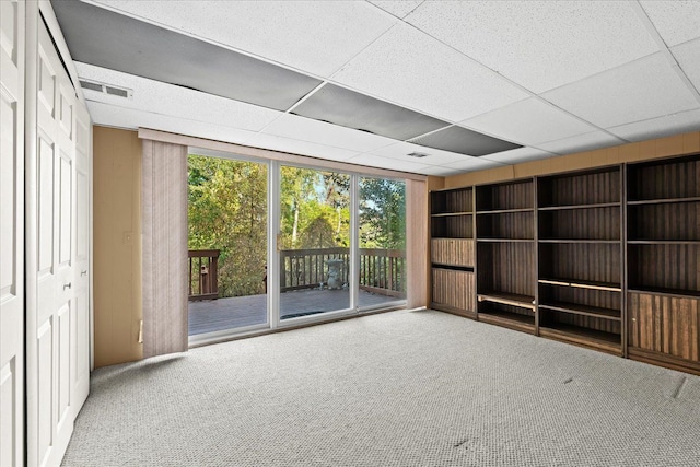 unfurnished living room featuring a paneled ceiling and carpet floors