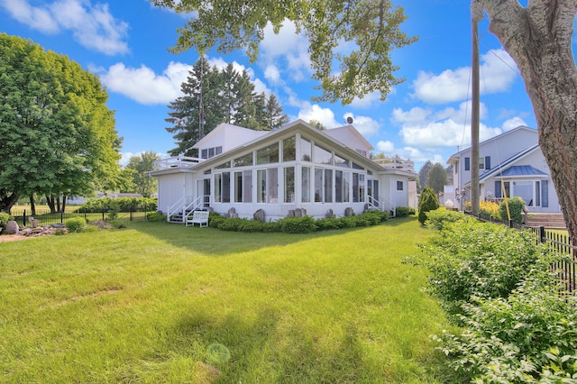 rear view of property featuring a sunroom and a yard