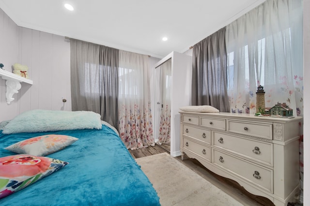 bedroom with wood walls, wood-type flooring, and ornamental molding