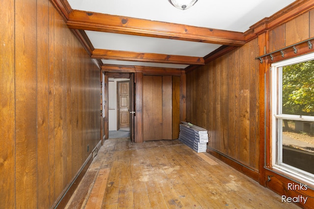 interior space featuring beam ceiling, light hardwood / wood-style flooring, and wooden walls