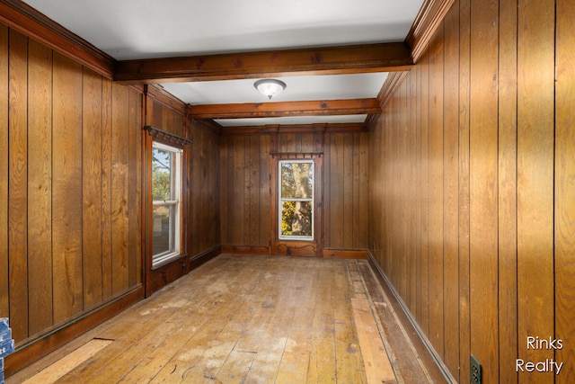 unfurnished room featuring beam ceiling, light wood-type flooring, and wooden walls