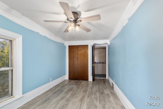 unfurnished bedroom featuring a closet, light hardwood / wood-style flooring, ceiling fan, and crown molding