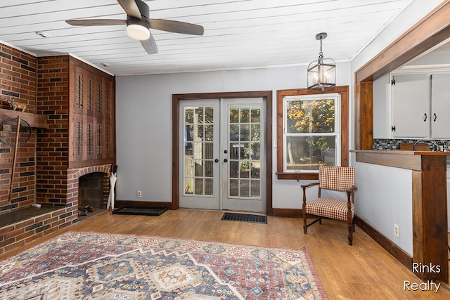 sitting room featuring wooden ceiling, french doors, a brick fireplace, ceiling fan, and light hardwood / wood-style floors