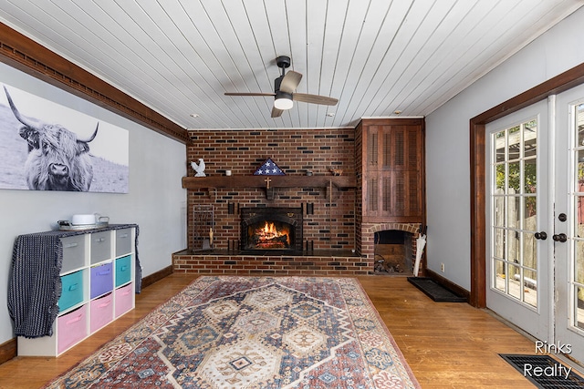 living room with light wood-type flooring, a brick fireplace, ceiling fan, and wood ceiling