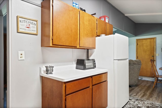 kitchen featuring white refrigerator, dark hardwood / wood-style flooring, and vaulted ceiling