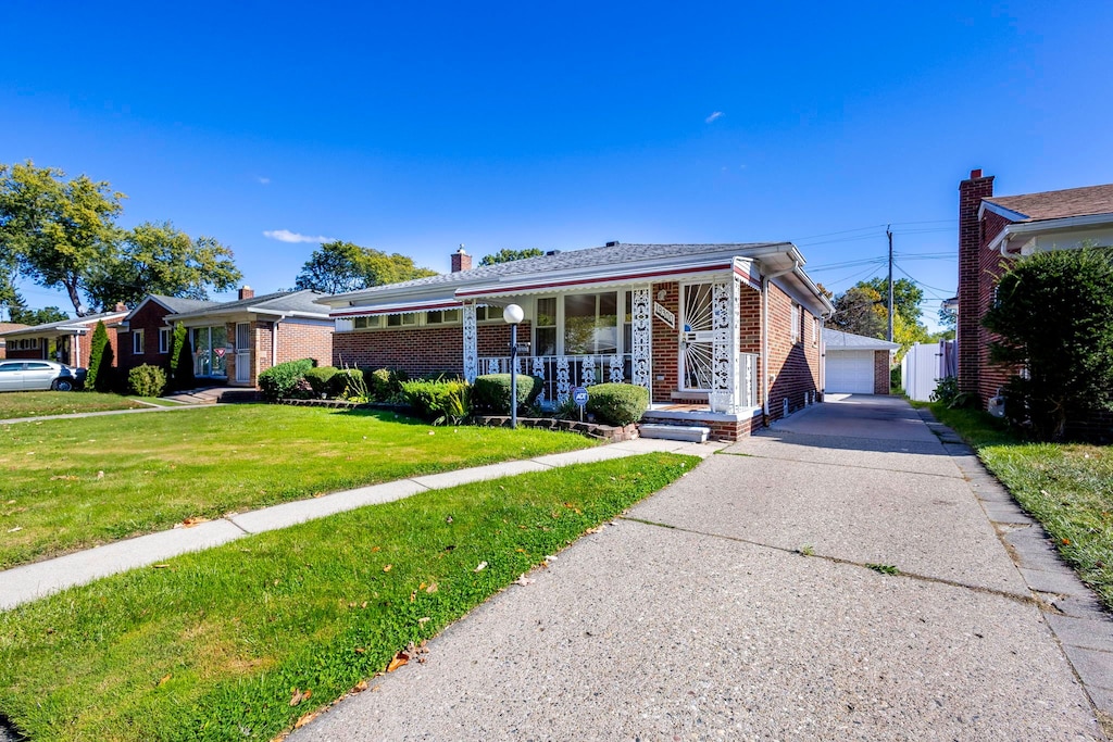 view of front of house with an outbuilding, a front lawn, covered porch, and a garage