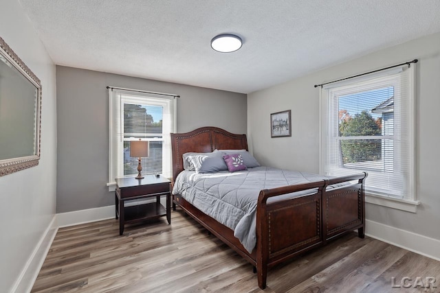 bedroom featuring multiple windows, wood-type flooring, and a textured ceiling