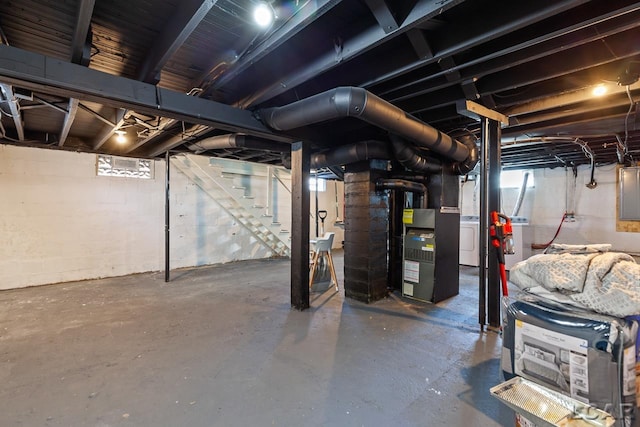 basement featuring electric panel, heating unit, and washer / dryer