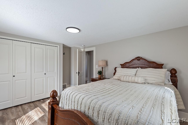 bedroom with a closet, a textured ceiling, and light hardwood / wood-style flooring