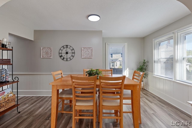 dining space with wood-type flooring and a textured ceiling