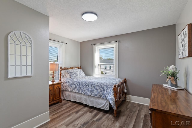 bedroom with a textured ceiling, multiple windows, and dark wood-type flooring