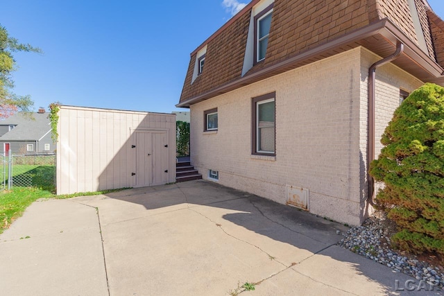 view of side of home with a storage unit and a patio area