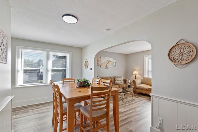 dining space with a textured ceiling and light hardwood / wood-style flooring