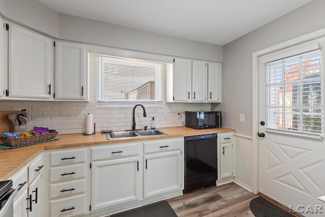 kitchen with sink, white cabinets, black appliances, and light wood-type flooring