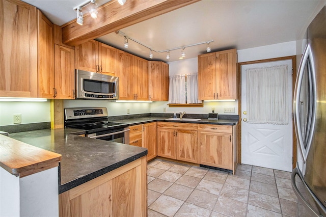 kitchen featuring kitchen peninsula, appliances with stainless steel finishes, rail lighting, and sink