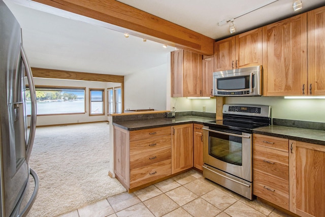 kitchen with kitchen peninsula, appliances with stainless steel finishes, track lighting, and light tile patterned flooring