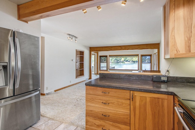 kitchen with appliances with stainless steel finishes, track lighting, and light tile patterned flooring