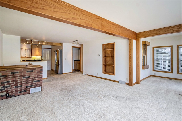 unfurnished living room featuring light carpet and track lighting