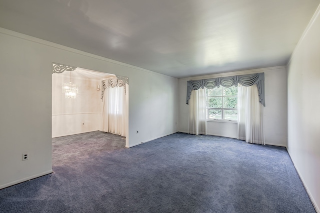 spare room with crown molding, dark carpet, and a notable chandelier