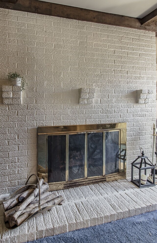 details with beamed ceiling, a fireplace, and carpet