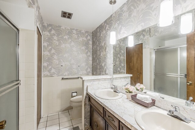 bathroom featuring walk in shower, tile patterned floors, toilet, vanity, and tile walls