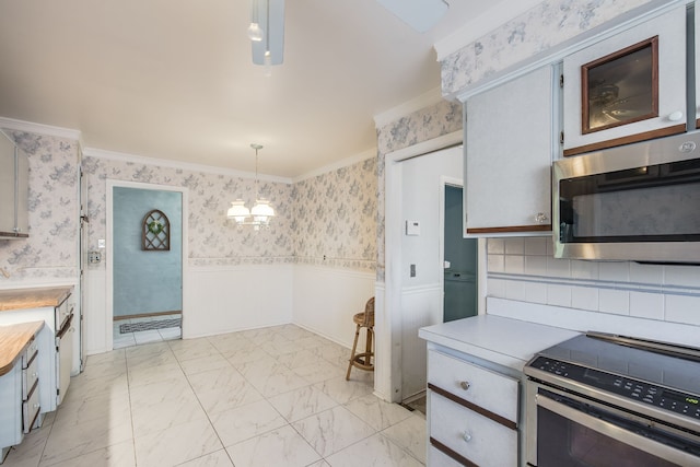 kitchen with appliances with stainless steel finishes, decorative light fixtures, crown molding, and a notable chandelier