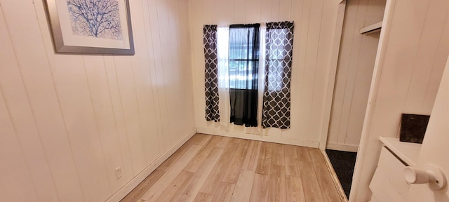 empty room featuring wooden walls and light hardwood / wood-style flooring