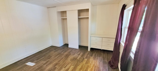 unfurnished bedroom featuring dark hardwood / wood-style floors, a closet, and multiple windows