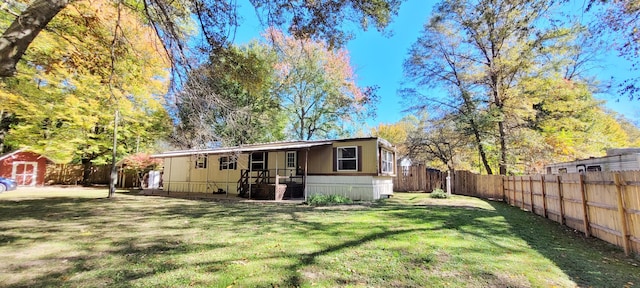 rear view of property with a lawn and a storage shed