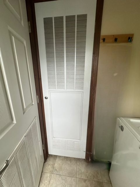 clothes washing area featuring light tile patterned flooring and washer / dryer