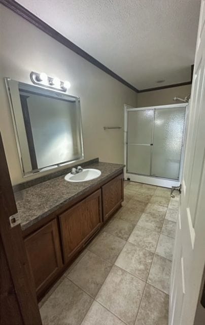 bathroom with crown molding, vanity, a textured ceiling, and walk in shower