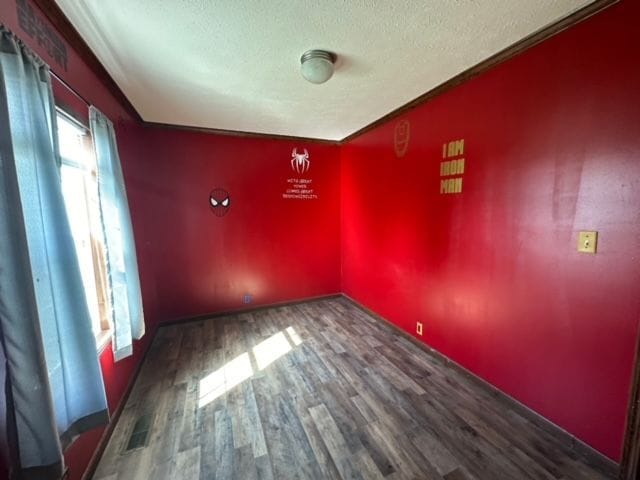 unfurnished room featuring plenty of natural light, dark wood-type flooring, and a textured ceiling