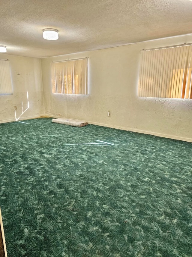 spare room featuring dark carpet and a textured ceiling