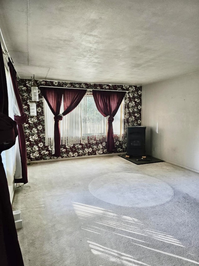 interior space with carpet, a wood stove, and a textured ceiling