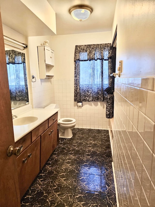 bathroom featuring a wealth of natural light, vanity, tile walls, and toilet