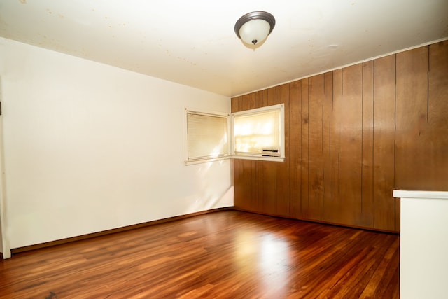 unfurnished room with wooden walls and dark hardwood / wood-style flooring