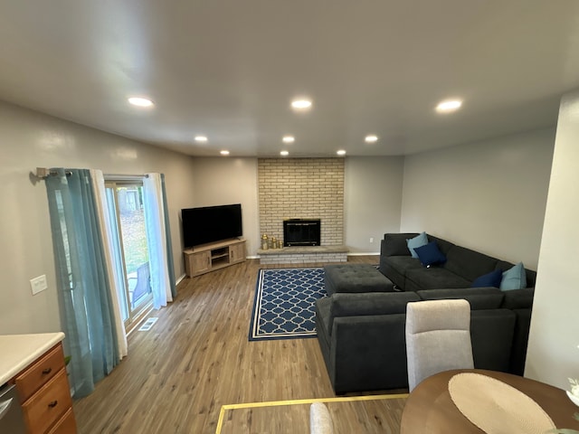 living room featuring light hardwood / wood-style floors and a brick fireplace