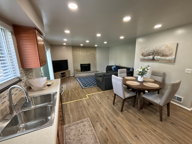 dining area with a fireplace, hardwood / wood-style flooring, a wealth of natural light, and sink