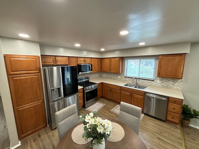 kitchen featuring decorative backsplash, sink, stainless steel appliances, and light hardwood / wood-style flooring