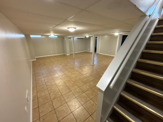 basement featuring a drop ceiling and light tile patterned floors