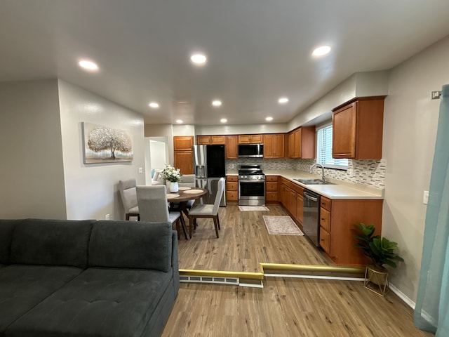 kitchen with decorative backsplash, sink, stainless steel appliances, and light hardwood / wood-style flooring