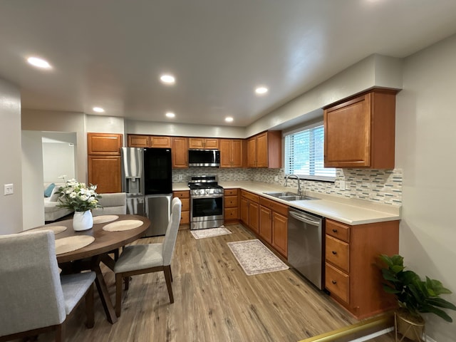 kitchen featuring decorative backsplash, sink, stainless steel appliances, and light hardwood / wood-style flooring