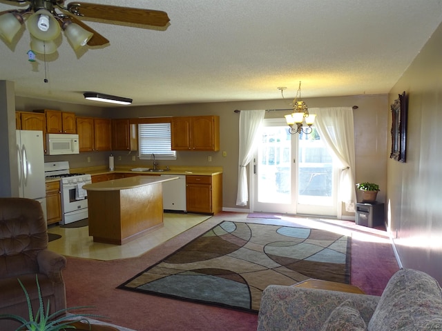 kitchen with sink, a textured ceiling, decorative light fixtures, white appliances, and a kitchen island